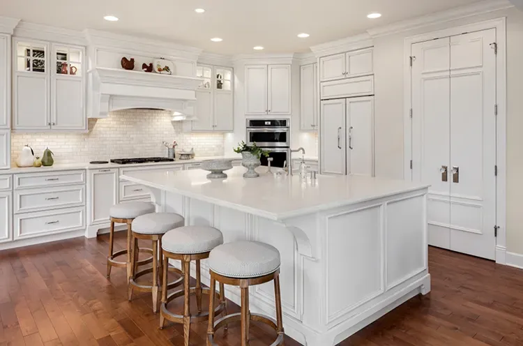 White kitchen cabinets and a large white island refinished by Elegant Edge Painting.