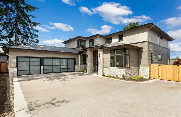 Contemporary two-story home in warm taupe siding with stone accents after an exterior repaint by Elegant Edge Painting.