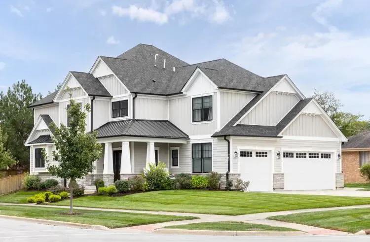 White board-and-batten home with a gray roof and covered front porch after an exterior repaint by Elegant Edge Painting.