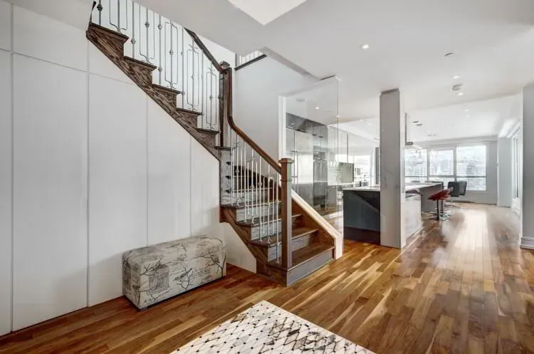 Entry hall with white walls and a stained wood staircase after an interior repaint by Elegant Edge Painting.