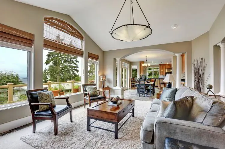 Bright living room with warm beige walls and a vaulted ceiling opening to the dining room after an interior repaint by Elegant Edge Painting.