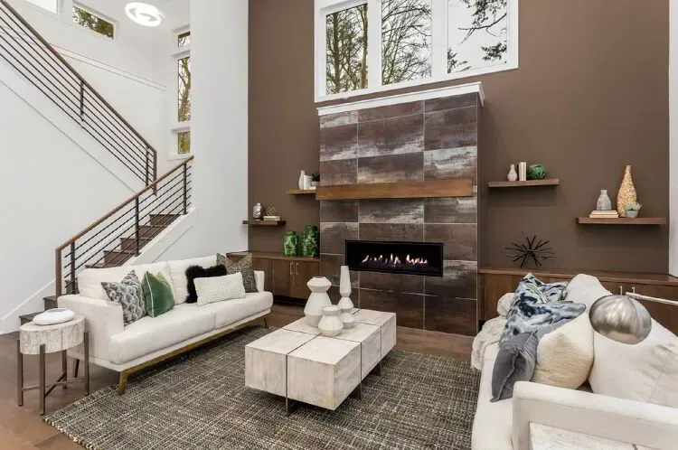 Living room with a chocolate brown accent wall around a tiled fireplace after an interior repaint by Elegant Edge Painting.