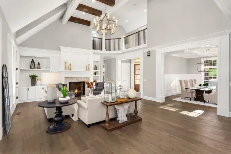 White great room with a brick fireplace, built-ins, and an open balcony after an interior repaint by Elegant Edge Painting.
