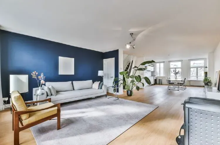 Open living area with a deep navy accent wall and white walls after an interior repaint by Elegant Edge Painting.
