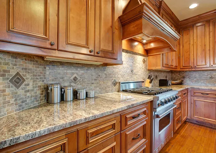 Kitchen with warm honey-stained wood cabinets and a matching range hood, with a fresh stain by Elegant Edge Painting.
