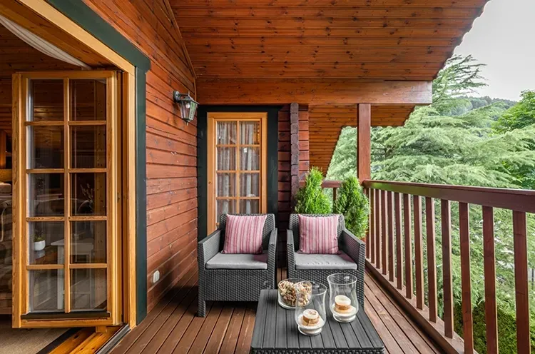 Covered wood balcony with stained siding, ceiling, and railings, with a fresh stain by Elegant Edge Painting.