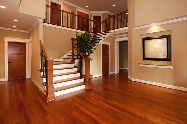 Entry with a stained wood staircase, doors, and hardwood floors, with a fresh stain by Elegant Edge Painting.